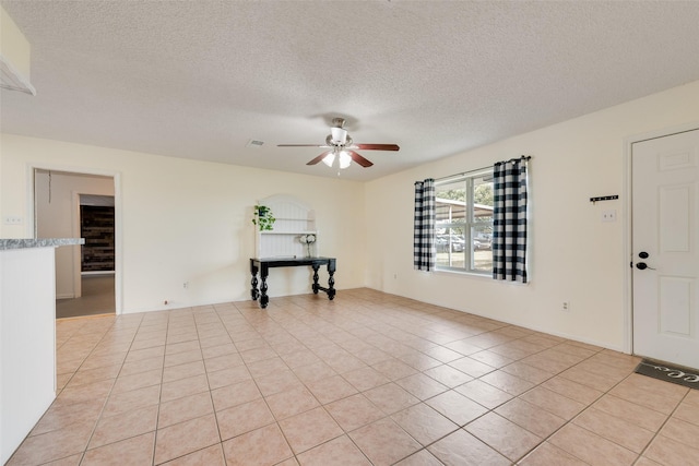 unfurnished room featuring ceiling fan, light tile patterned floors, and a textured ceiling