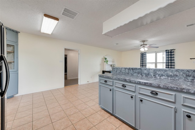 kitchen featuring ceiling fan, light tile patterned flooring, and a textured ceiling