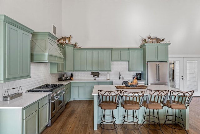 kitchen with premium appliances, a breakfast bar, green cabinetry, and premium range hood