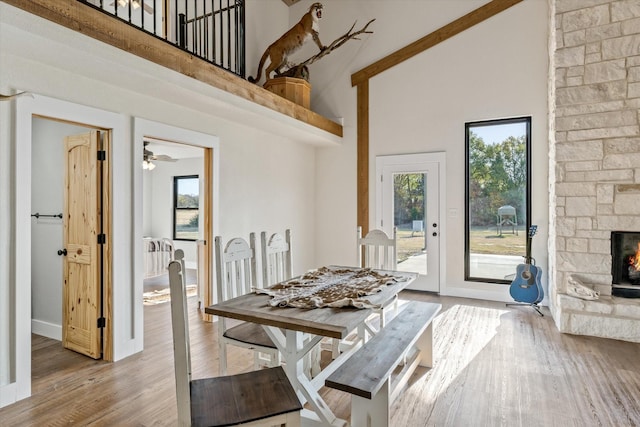 dining room featuring high vaulted ceiling, a fireplace, and wood finished floors