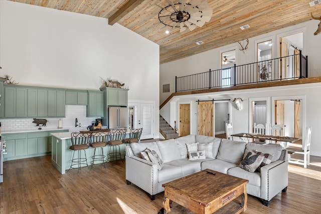 living area featuring wooden ceiling, a barn door, high vaulted ceiling, and wood finished floors