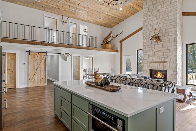 kitchen featuring high vaulted ceiling, a stone fireplace, wood ceiling, dark wood-style floors, and green cabinetry