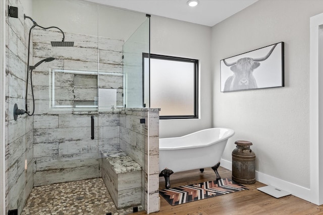 bathroom with a stall shower, baseboards, wood finished floors, and a soaking tub