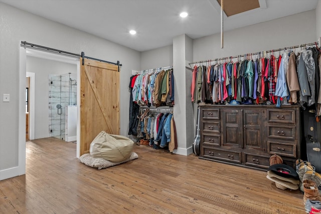 walk in closet featuring a barn door and wood finished floors