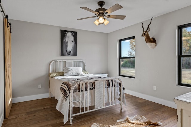 bedroom with a barn door, multiple windows, and wood finished floors