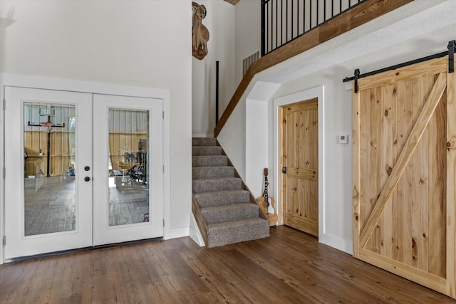 entryway featuring stairs, wood finished floors, a towering ceiling, and a barn door