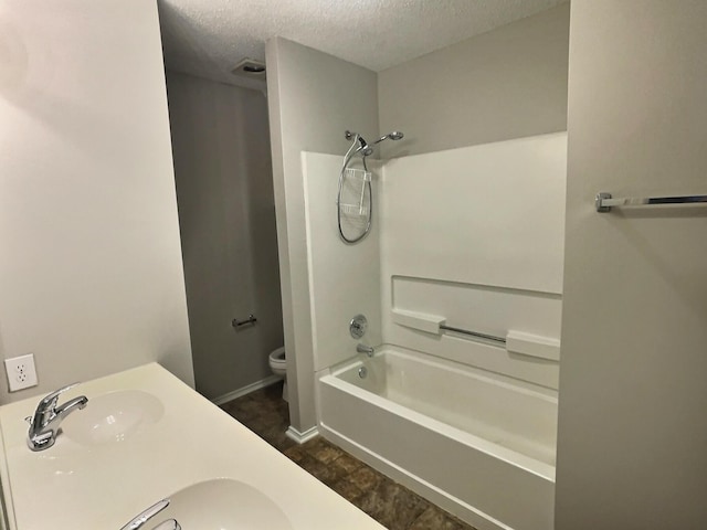 full bath with shower / bath combination, double vanity, toilet, a textured ceiling, and a sink