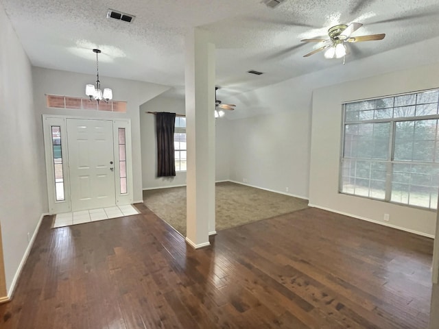 entryway featuring ceiling fan with notable chandelier, dark wood-style flooring, a textured ceiling, and visible vents