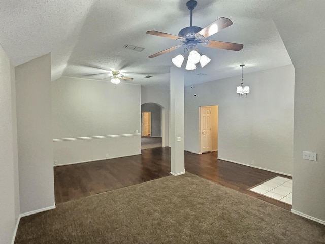 unfurnished living room featuring visible vents, arched walkways, lofted ceiling, a textured ceiling, and dark carpet