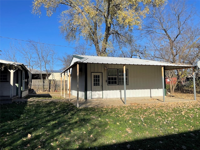 exterior space featuring metal roof, a lawn, an outdoor structure, and fence