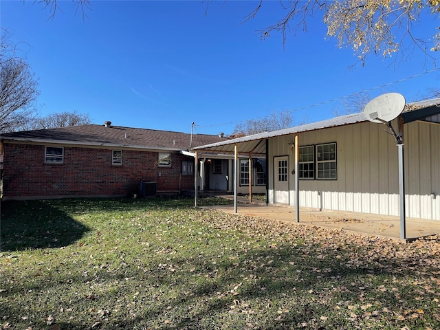 rear view of property with a lawn, central AC, and brick siding