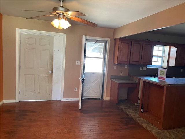 kitchen with baseboards, dark wood finished floors, a wealth of natural light, and brown cabinets