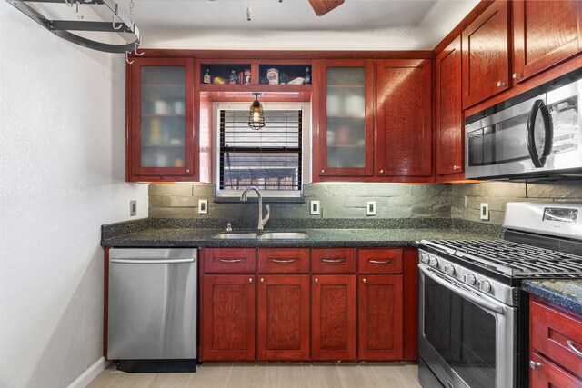 kitchen with ceiling fan, sink, tasteful backsplash, dark stone counters, and appliances with stainless steel finishes