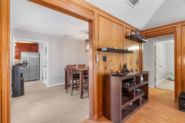 kitchen with a textured ceiling, stainless steel fridge, and light wood-type flooring