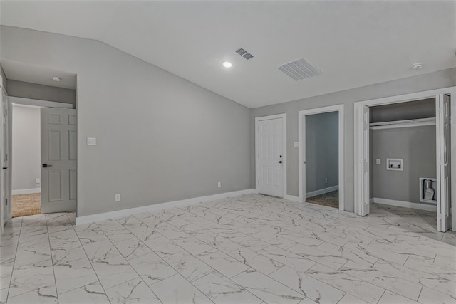 unfurnished bedroom featuring visible vents, marble finish floor, two closets, and vaulted ceiling