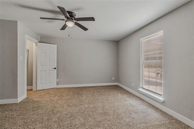 carpeted empty room with ceiling fan and baseboards