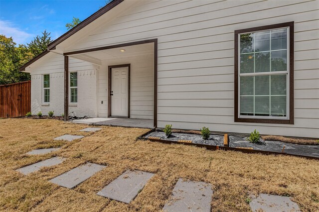 property entrance with a lawn and fence