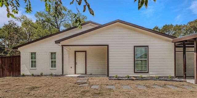 view of front of house featuring brick siding and fence