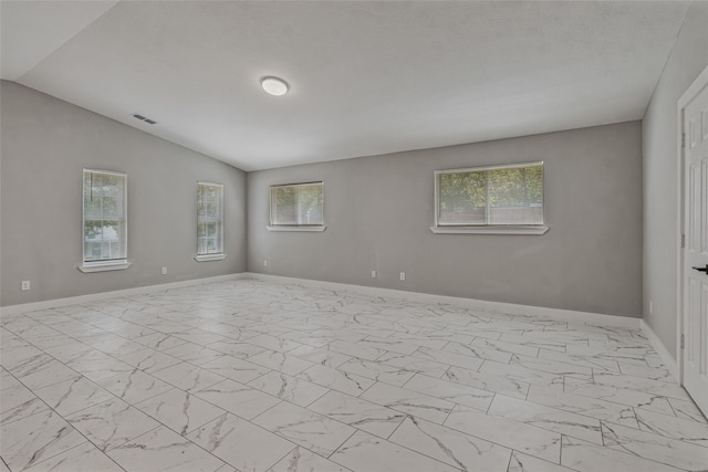 spare room with baseboards, visible vents, vaulted ceiling, and marble finish floor
