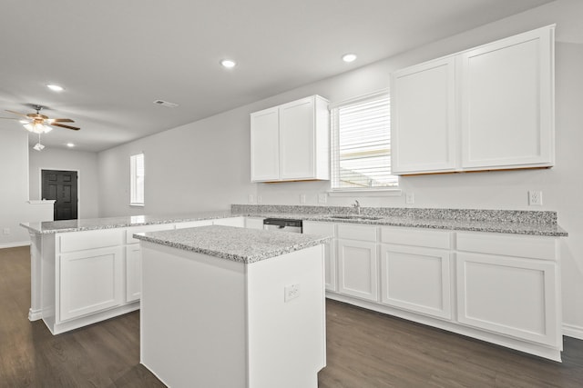 kitchen featuring dark hardwood / wood-style floors, sink, white cabinets, a center island, and kitchen peninsula