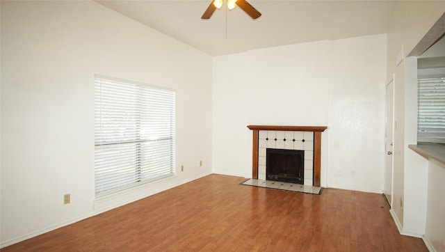 unfurnished living room featuring ceiling fan, a tiled fireplace, and hardwood / wood-style floors