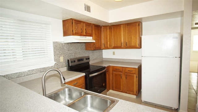 kitchen with electric stove, sink, light tile patterned floors, tasteful backsplash, and white fridge