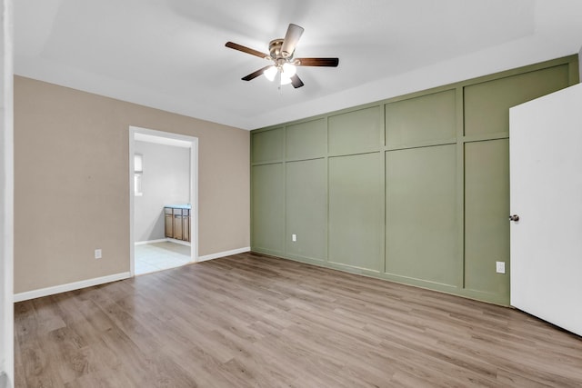 unfurnished bedroom featuring a closet, connected bathroom, ceiling fan, and light hardwood / wood-style flooring