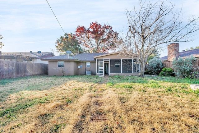 rear view of property with a sunroom, a yard, and central AC