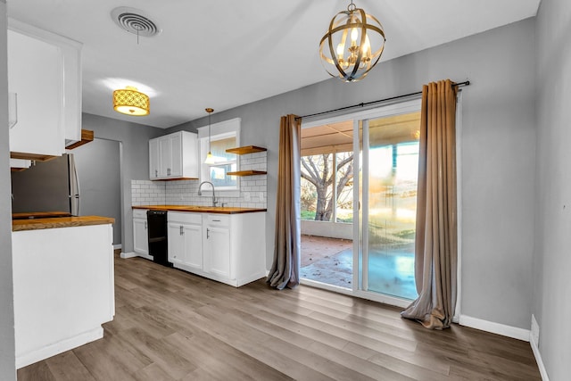 kitchen featuring wood counters, white cabinetry, black dishwasher, and decorative light fixtures