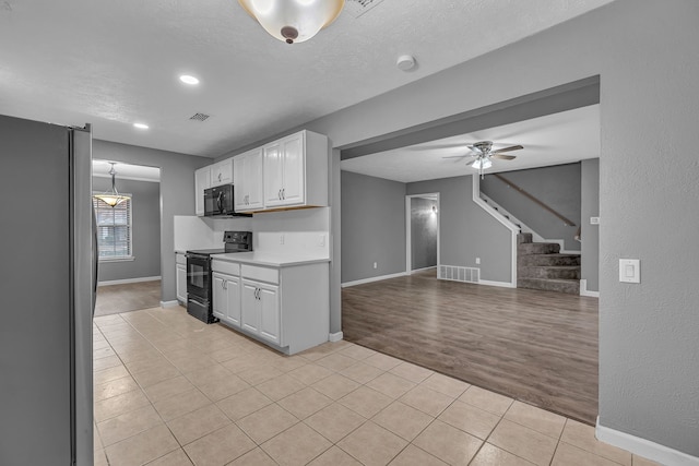 kitchen featuring white cabinetry, light tile patterned floors, ceiling fan, black appliances, and a textured ceiling