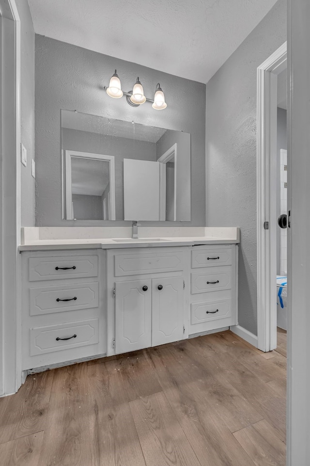 bathroom with vanity, wood-type flooring, and a textured ceiling