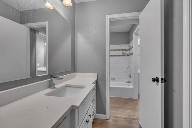 bathroom with vanity, wood-type flooring, and tiled shower / bath