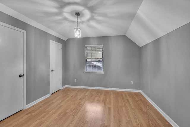 additional living space with vaulted ceiling and light wood-type flooring