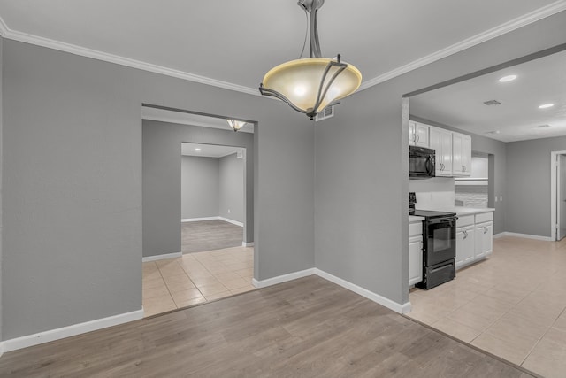 interior space with pendant lighting, ornamental molding, black appliances, and white cabinets