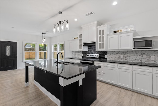 kitchen with sink, stainless steel appliances, pendant lighting, light hardwood / wood-style floors, and a center island with sink