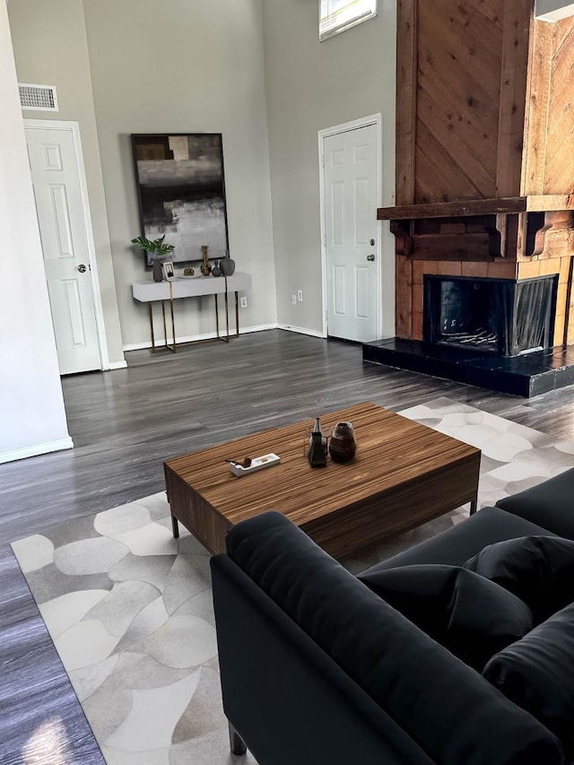 living room with hardwood / wood-style flooring, a large fireplace, and a towering ceiling