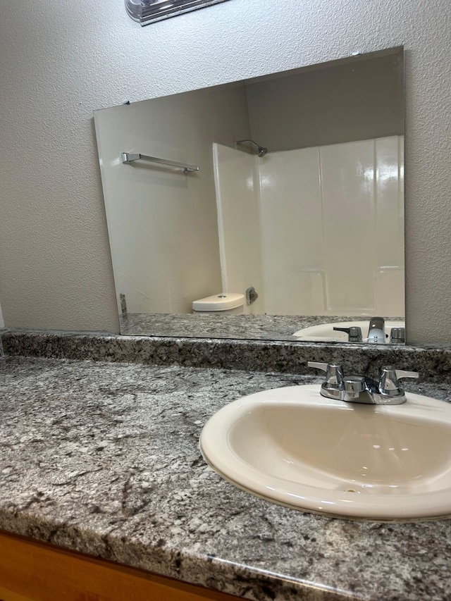 bathroom with toilet, walk in shower, and vanity