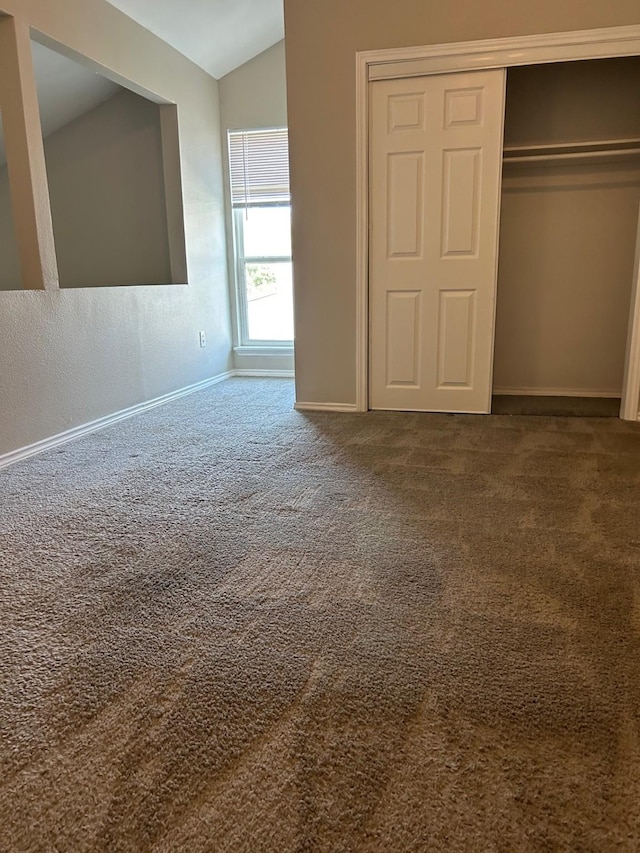 unfurnished bedroom featuring carpet flooring, a closet, and vaulted ceiling