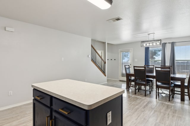 kitchen featuring a kitchen island, hanging light fixtures, a textured ceiling, and light wood-type flooring