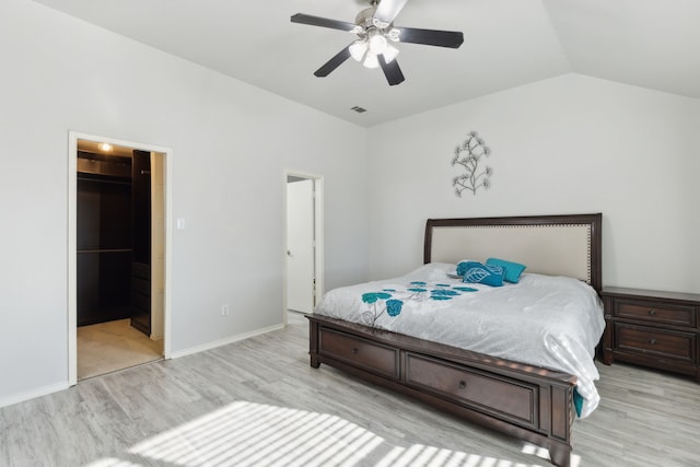 bedroom featuring a spacious closet, light hardwood / wood-style flooring, ceiling fan, and lofted ceiling