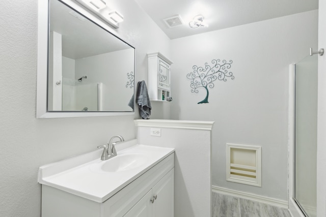 bathroom featuring a shower with door, vanity, and hardwood / wood-style flooring