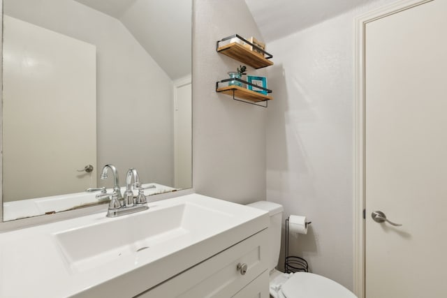 bathroom with vanity, vaulted ceiling, and toilet