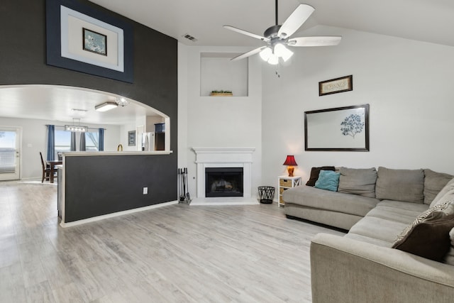 living room with light wood-type flooring, vaulted ceiling, and ceiling fan