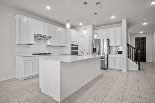 kitchen with light tile patterned floors, visible vents, an island with sink, appliances with stainless steel finishes, and under cabinet range hood