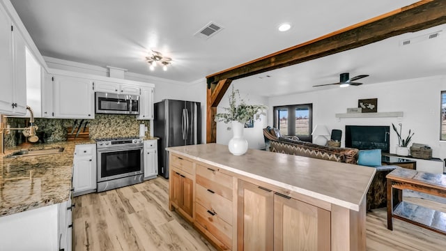 kitchen featuring a center island, white cabinets, crown molding, light hardwood / wood-style floors, and stainless steel appliances