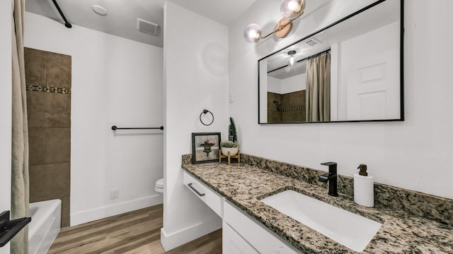 full bathroom featuring toilet, vanity, tiled shower / bath combo, and hardwood / wood-style flooring