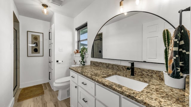 bathroom with vanity, toilet, wood-type flooring, and a shower with door