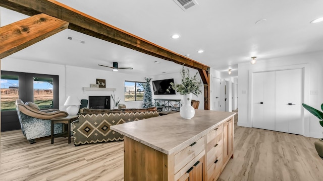 kitchen featuring light brown cabinetry, a kitchen island, light hardwood / wood-style flooring, and a healthy amount of sunlight