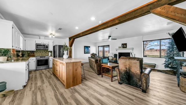 kitchen featuring a center island, white cabinets, ceiling fan, light wood-type flooring, and stainless steel appliances