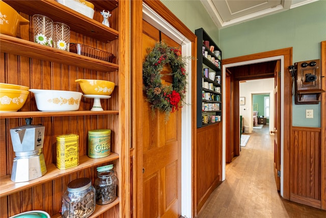 corridor with ornamental molding and light hardwood / wood-style flooring